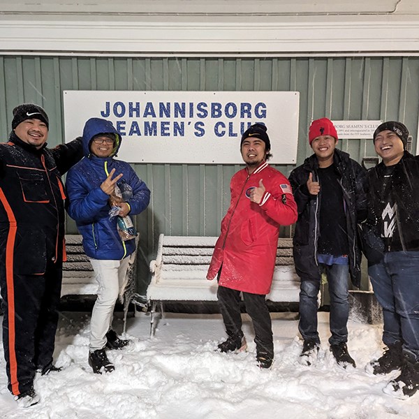 Some visitors in the snow, in front of the sign saying Johannisborg Seamen's Club