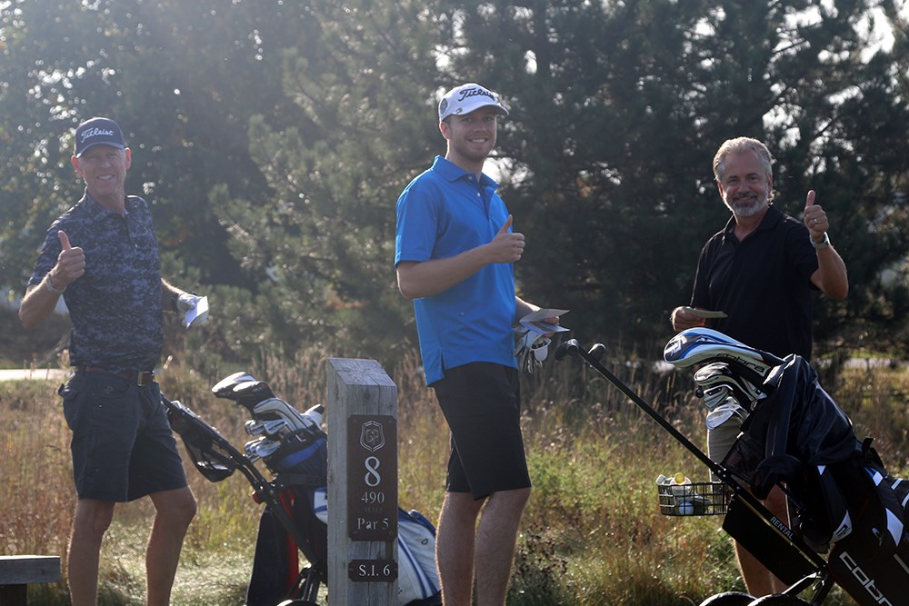 Tre golfspelare ler mot kameran och gör "tumme upp"