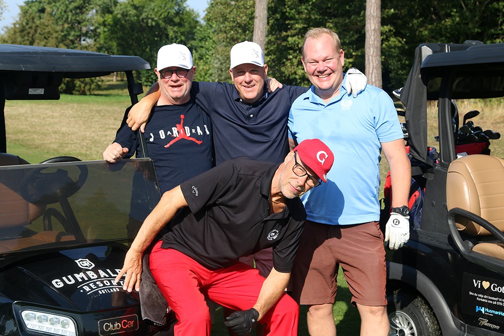 Fyra golfspelare blickar in i kameran, varav en sitter på motorhuven på en golfbil