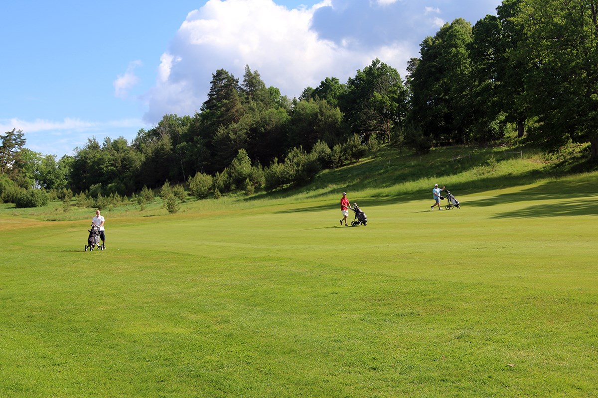 Tre golfspelare går på banan